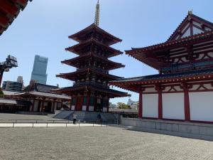 a person standing in front of two large buildings at guest house Sakura in Osaka