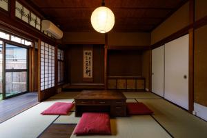 um quarto com tapetes, uma mesa e um candeeiro em Tsunagian TABI-NE em Kanazawa