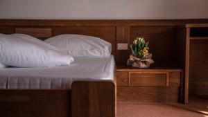 a bed with white pillows and a plant on a table at Hotel Traubenwirt in Marlengo
