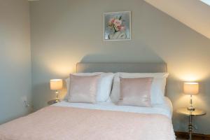 a bedroom with a bed with white pillows and two lamps at Queen Anne's Home in Great Yarmouth