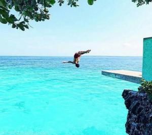 a man jumping into the water on a skateboard at First Baby Bytes Guest House in Lazi