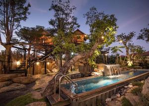 a swimming pool with a tree and a house at Na Klongluang Boutique Resort in Ban Khlong Nung