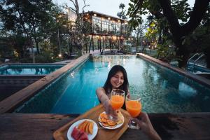 a woman sitting at a table with two glasses of orange juice at Na Klongluang Boutique Resort in Ban Khlong Nung