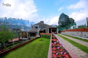 a garden with flowers in front of a house at snow drop villa in Kodaikānāl