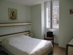 a bedroom with a bed and a chair and a window at Pub Vauban in Avallon