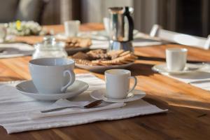 una mesa de madera con dos tazas y un plato de comida en La Casa dell Olivo, en Castiadas