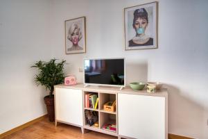 una sala de estar con un centro de entretenimiento blanco con TV en CaseOspitali - CASA DIVA monolocale in centro storico, en Cernusco sul Naviglio