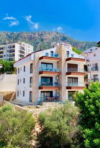 a large white building with a mountain in the background at Blue View Suites Kaş in Kaş