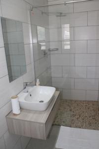 a white bathroom with a sink and a mirror at Milo's Sky Grey Guest House - No Load shedding in Cape Town