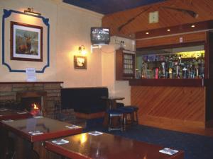 a bar with a fireplace and a tv in a room at Ecclefechan Hotel in Ecclefechan