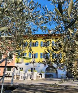 um edifício amarelo e branco com uma árvore em frente em Dolceresio Lugano Lake B&B em Brusino Arsizio