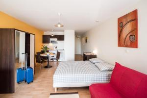 a living room with a bed and a red couch at Residences de Bougainville in Rochefort