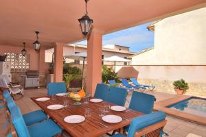 drewniany stół i krzesła na patio z basenem w obiekcie 226 Villa Cas Barber ETV10939 by Mallorca Charme w mieście Muro