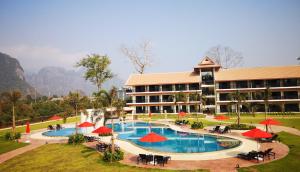 a resort with a large pool with tables and umbrellas at Tmark Resort Vangvieng in Vang Vieng