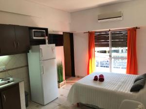 a kitchen with a refrigerator and two shoes on a bed at Cares Apartament, Morón, Buenos Aires in Morón