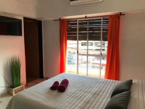 ein Schlafzimmer mit einem Bett mit roten Hausschuhen darauf in der Unterkunft Cares Apartament, Morón, Buenos Aires in Morón