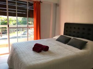 uma cama com duas almofadas e uma toalha em Cares Apartament, Morón, Buenos Aires em Morón