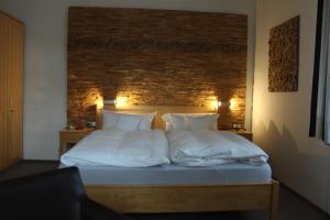 ein Bett mit weißer Bettwäsche und Kissen in einem Schlafzimmer in der Unterkunft Hotel Almrausch in Bad Reichenhall