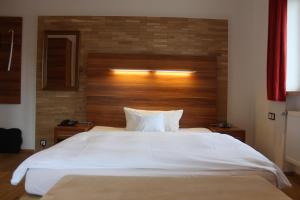 sypialnia z dużym białym łóżkiem z drewnianym zagłówkiem w obiekcie Hotel Almrausch w mieście Bad Reichenhall