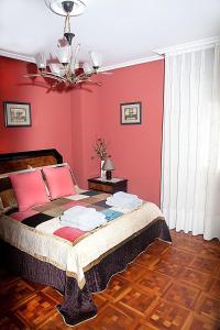 a bedroom with a bed with red walls and a chandelier at DUPLEX LLANES CENTRO-PLAYA, tranquilo y con garaje in Llanes