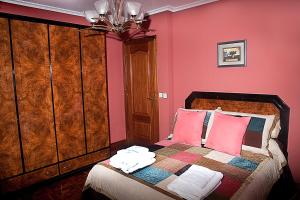 a bedroom with pink walls and a bed with pink pillows at DUPLEX LLANES CENTRO-PLAYA, tranquilo y con garaje in Llanes