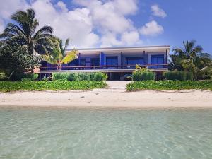 a house on a beach next to the water at Panama Beachfront Apartments, Rarotonga in Rarotonga