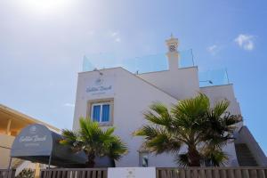 un edificio bianco con una torre dell'orologio sopra di Golden Beach Guest House & Rooftop Bar a Faro