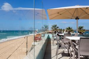 a beach area with chairs, tables and umbrellas at Golden Beach Guest House & Rooftop Bar in Faro