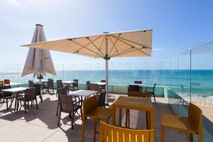 a patio area with chairs, tables and umbrellas at Golden Beach Guest House & Rooftop Bar in Faro