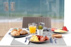 a breakfast table with plates of food and a glass of orange juice at Golden Beach Guest House & Rooftop Bar in Faro