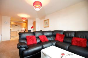 um sofá de couro preto com almofadas vermelhas numa sala de estar em Coventry Home em Coventry