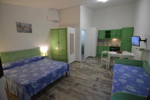 sypialnia z 2 łóżkami i kuchnia z zielonymi szafkami w obiekcie Residence L'Ulivo w mieście Budoni