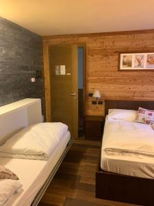 2 camas en una habitación con paredes de madera en Hosquet Lodge, en Breuil-Cervinia