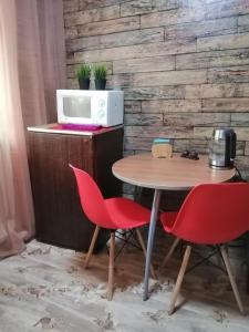 ノヴォクズネツクにあるAlways at home - Apartments at Klimasenko 11 block 7の電子レンジの前にテーブルと赤い椅子2脚