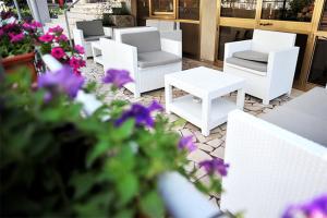 a group of white chairs and tables and purple flowers at Hotel Aquarius in Cattolica