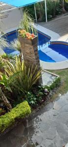 a garden with a fountain with flowers and a swimming pool at Cabañas La Finca in Atlixco