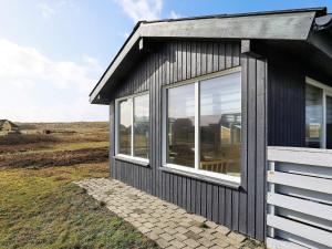 a black house with large windows on a field at 6 person holiday home in Lemvig in Ferring