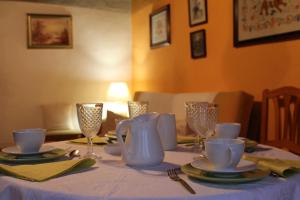 una mesa con jarra azul, platos y copas de vino en Casa de la Parra, en Mogarraz