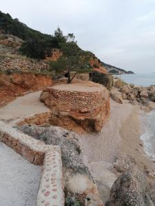 una estructura de piedra con un árbol en la playa en Apartments Berti, en Sveta Nedelja