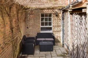 d'une terrasse avec des chaises et une fenêtre dans un bâtiment en briques. dans l'établissement Regency apartment - private entrance & courtyard, à Cheltenham