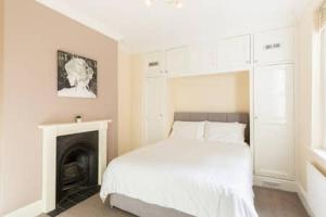 a white bedroom with a bed and a fireplace at Regency apartment - private entrance & courtyard in Cheltenham