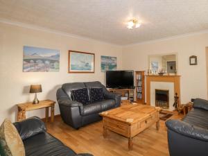 a living room with leather furniture and a fireplace at Braemar Cottage in Inver