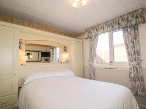a bedroom with a white bed and a window at Braemar Cottage in Inver