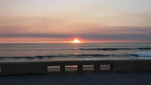 a bench on the beach with a sunset in the ocean at Villa Granja Sol in São Félix da Marinha