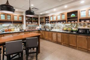 a large kitchen with wooden cabinets and a table and chairs at Hyatt Place Rogers/Bentonville in Rogers