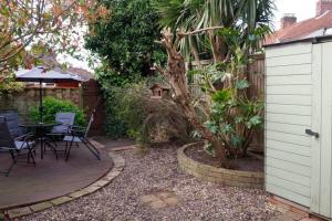 a garden with a tree and a table and chairs at Self contained stylish city home in Norwich