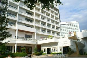 un gran edificio blanco con gente sentada fuera de él en Royal Palace Hotel, en Pattaya central