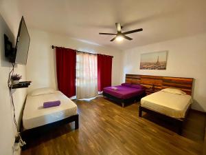 a room with two beds and a ceiling fan at Cancun-Soho in Cancún