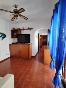 a living room with a ceiling fan and blue curtains at Apartamento Vargas in Monte Gordo