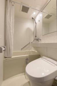 a white bathroom with a toilet and a bath tub at Shinbashi Urban Hotel in Tokyo